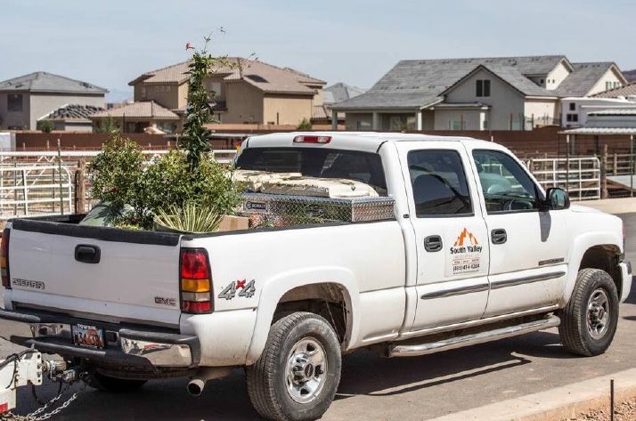 A white truck with a trailer attached to it is parked on the side of the road.