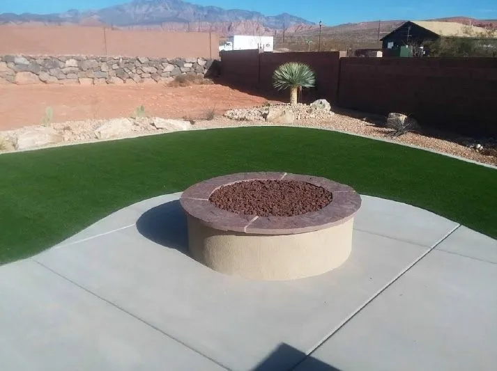 A fire pit in the middle of a lawn with mountains in the background