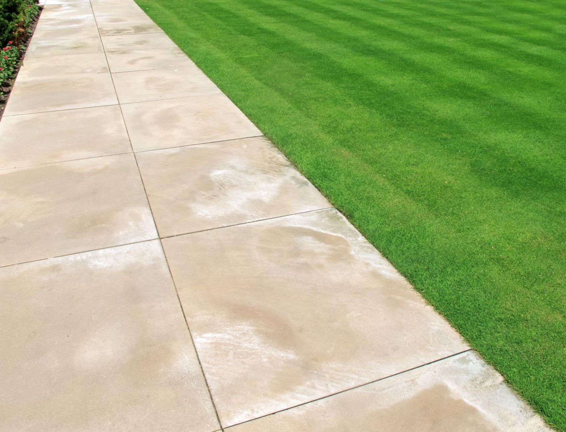 A concrete walkway leading to a lush green lawn