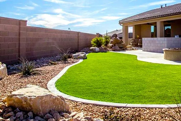 A backyard with a lush green lawn and a house in the background.