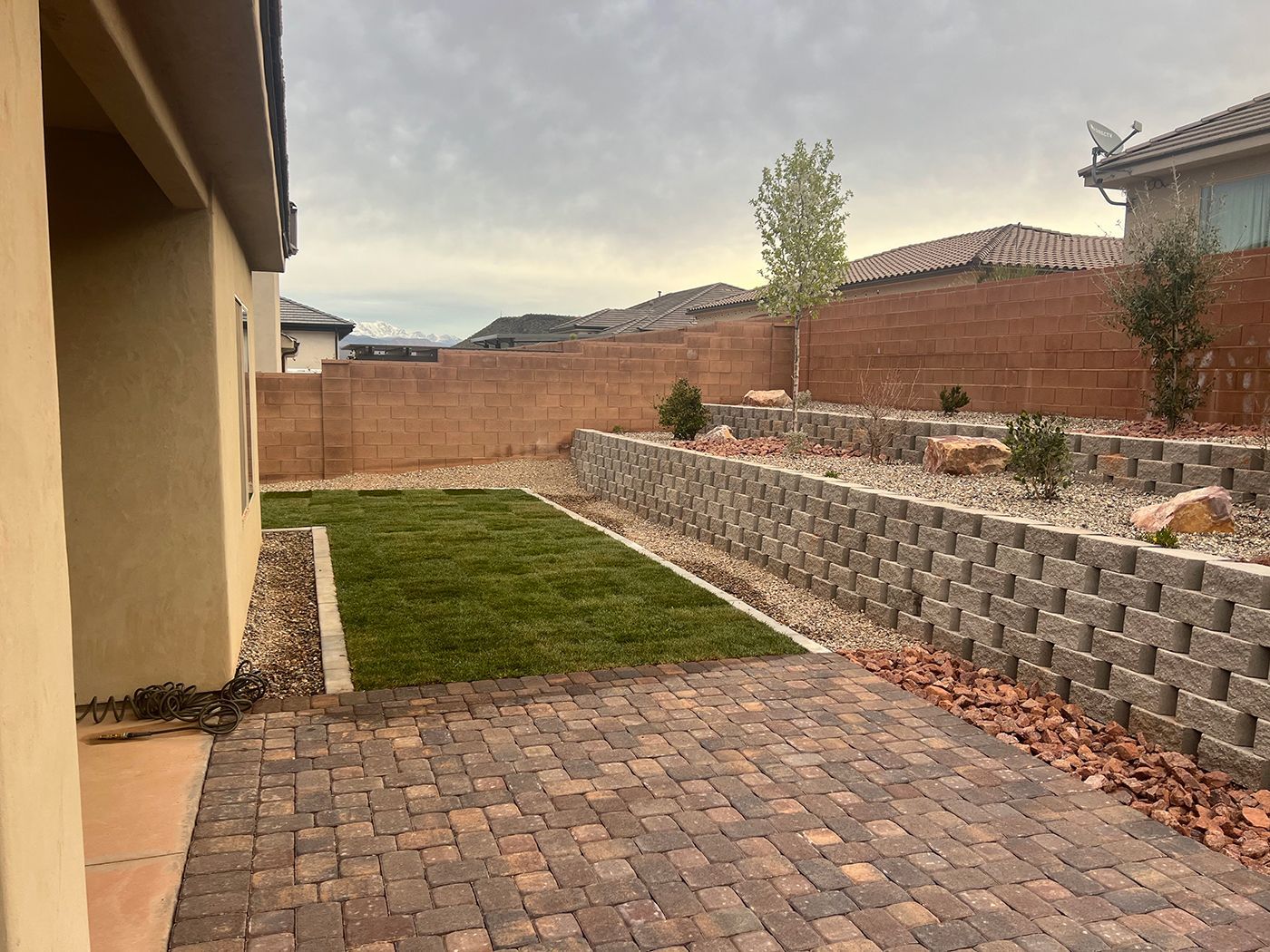 A backyard with a brick walkway and a brick wall.