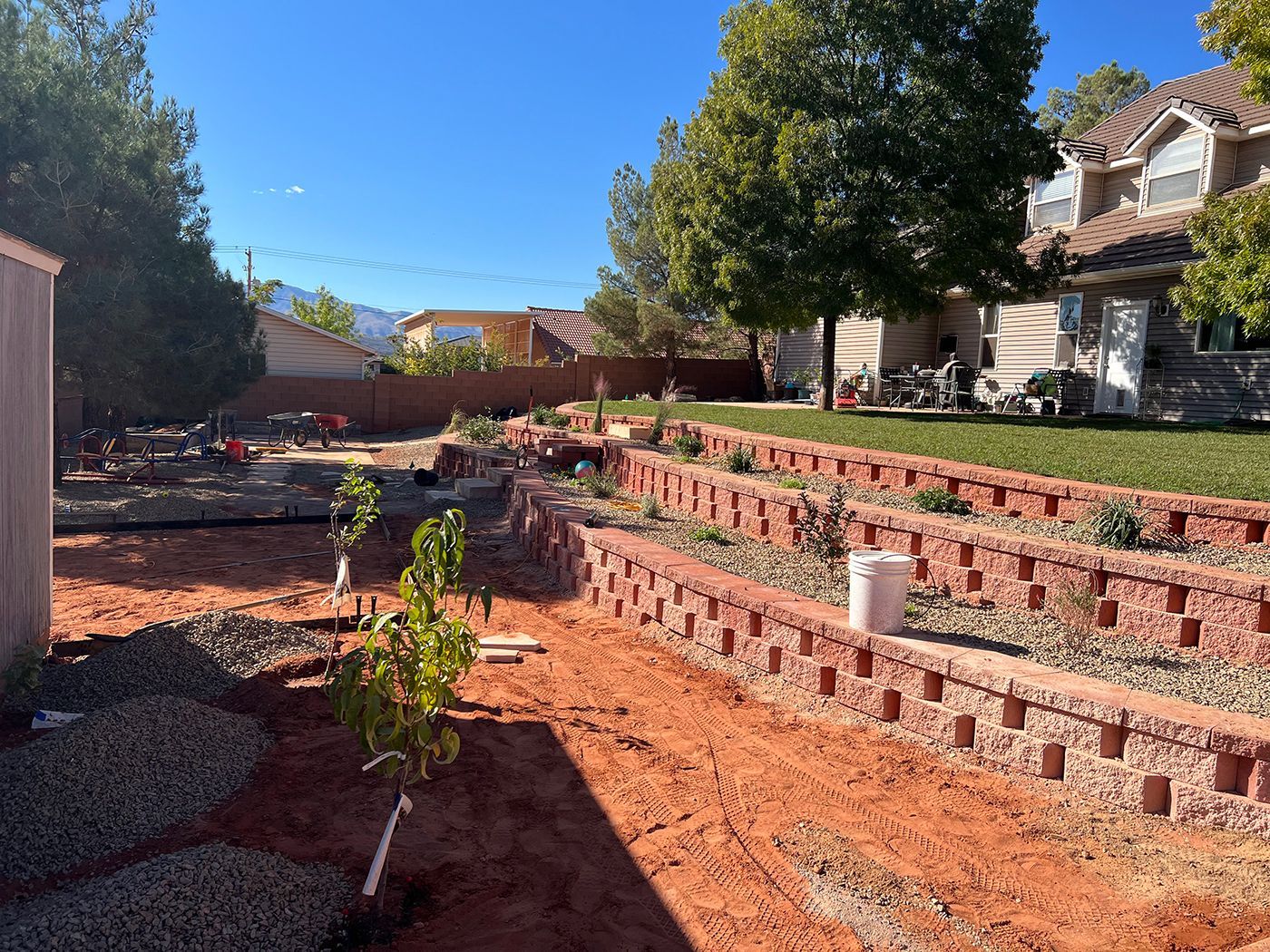 A brick wall is being built in the backyard of a house.