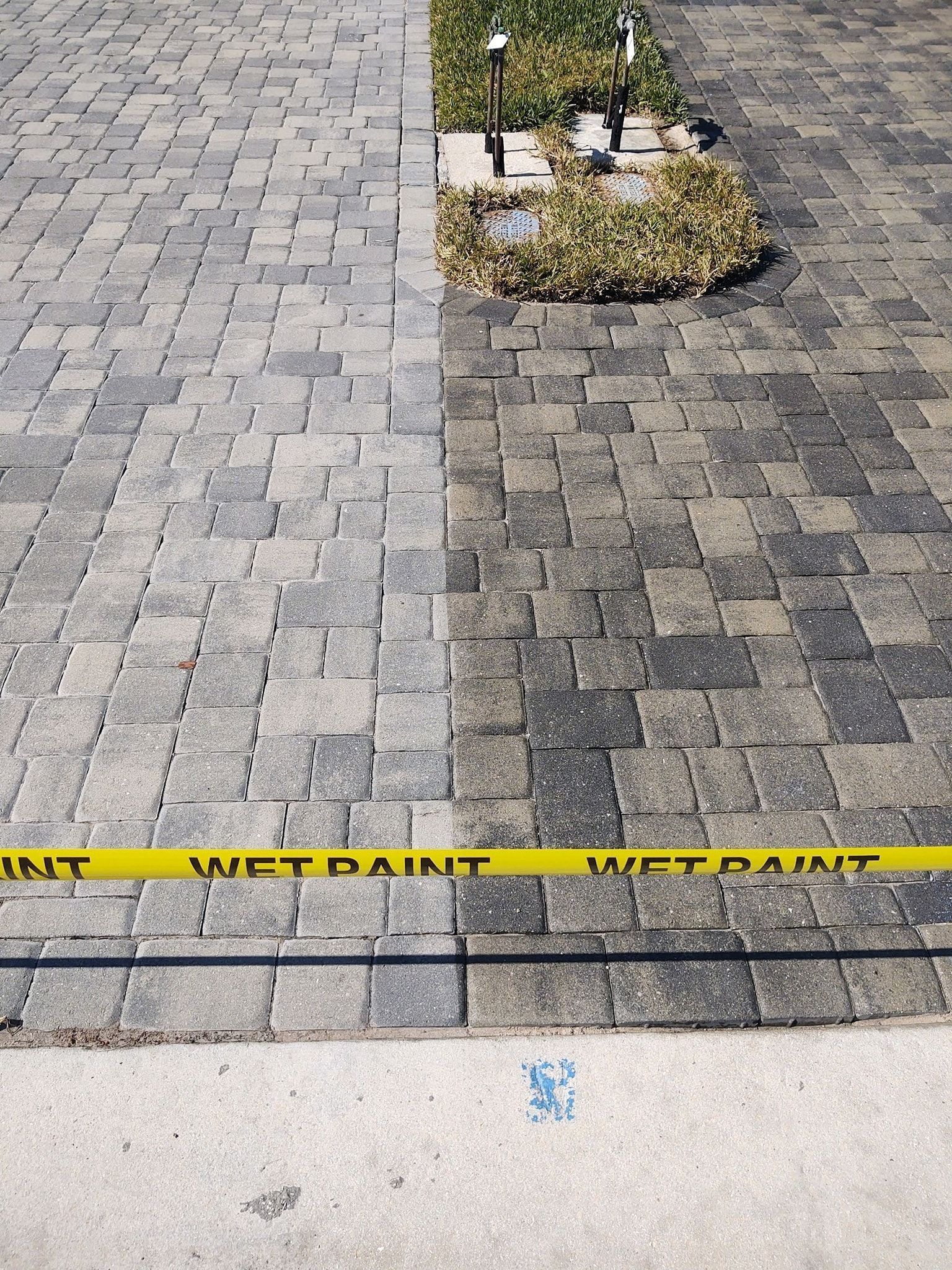 Paved walkway with yellow caution tape and a small planted area with white posts.