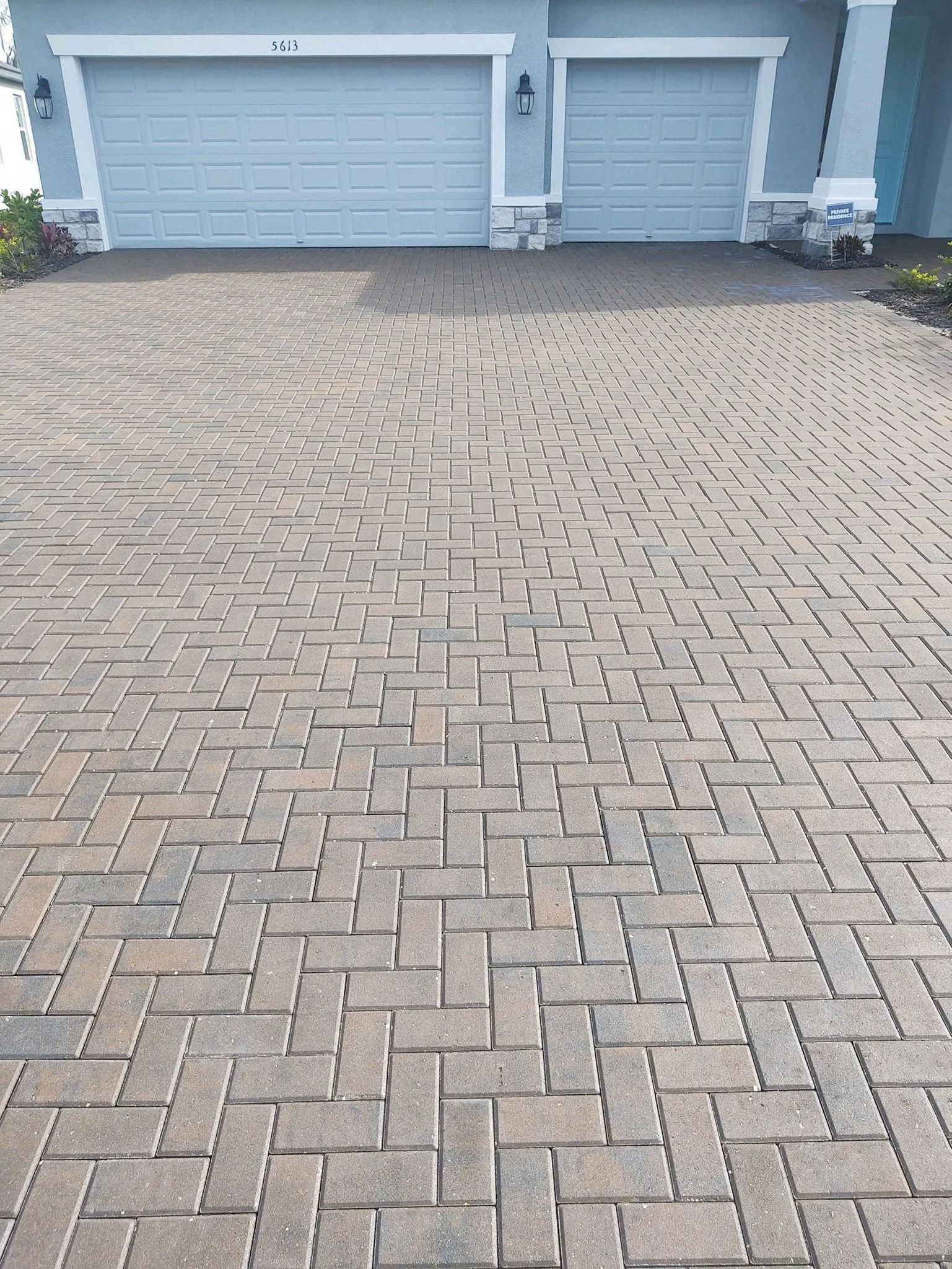 Paved driveway leading to two light blue garage doors on a house exterior