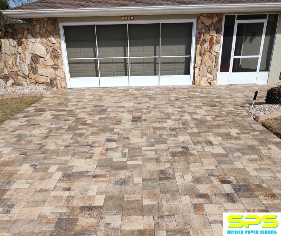 Stone-pattern paver driveway in front of a house with a garage door and side entry door