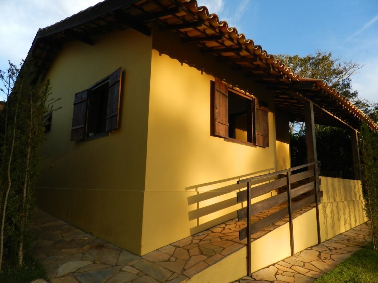 Casa térrea de cor bege com venezianas de madeira, varanda e rampa de acesso.