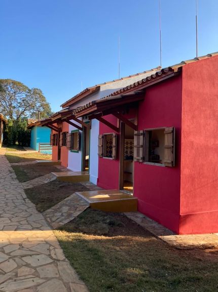 Casa amarela de estuque com persianas marrons, telhado de telha e rampa de acesso.
