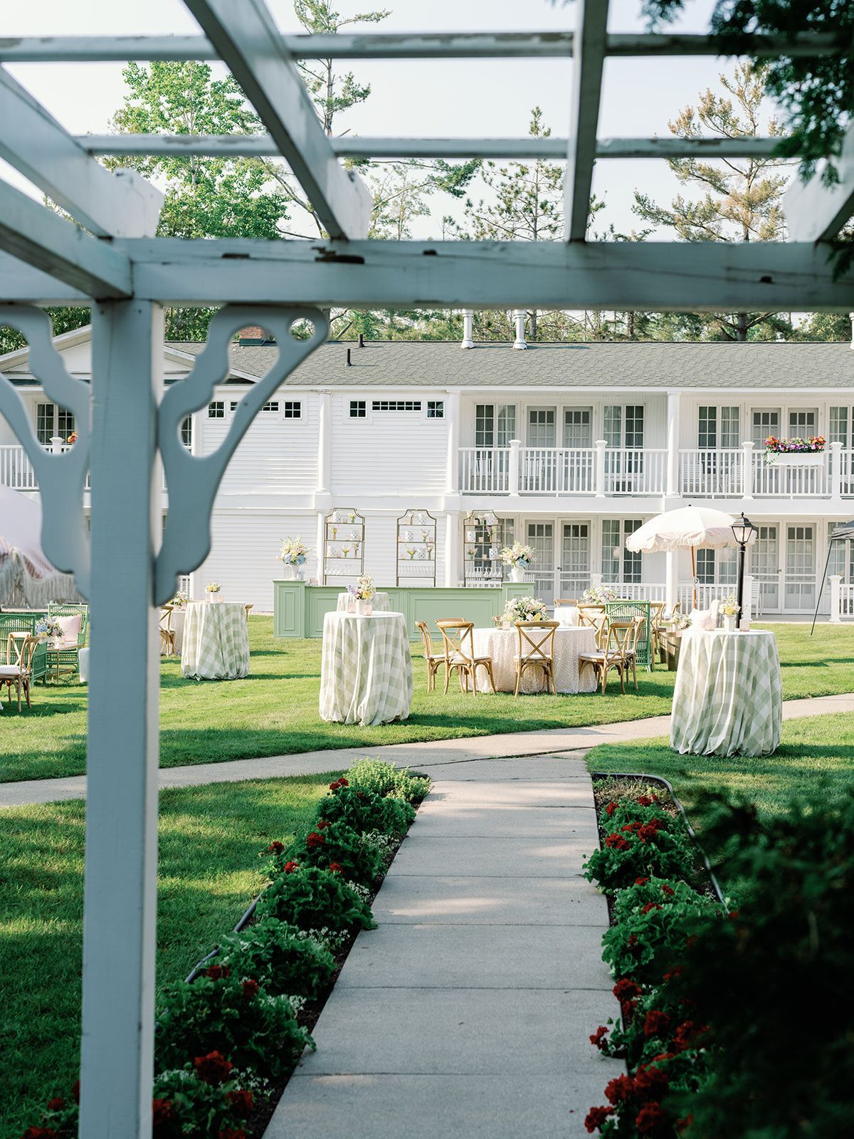 White house patio with a pergola, garden path, and outdoor seating in a landscaped yard.