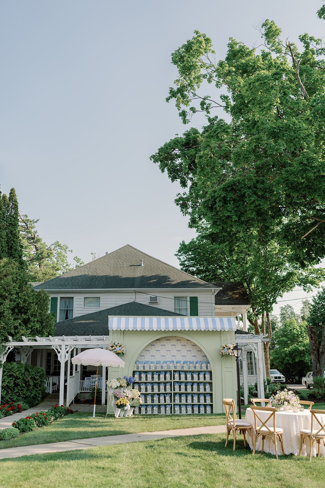 Two-story house with white arches and a garden patio under green trees