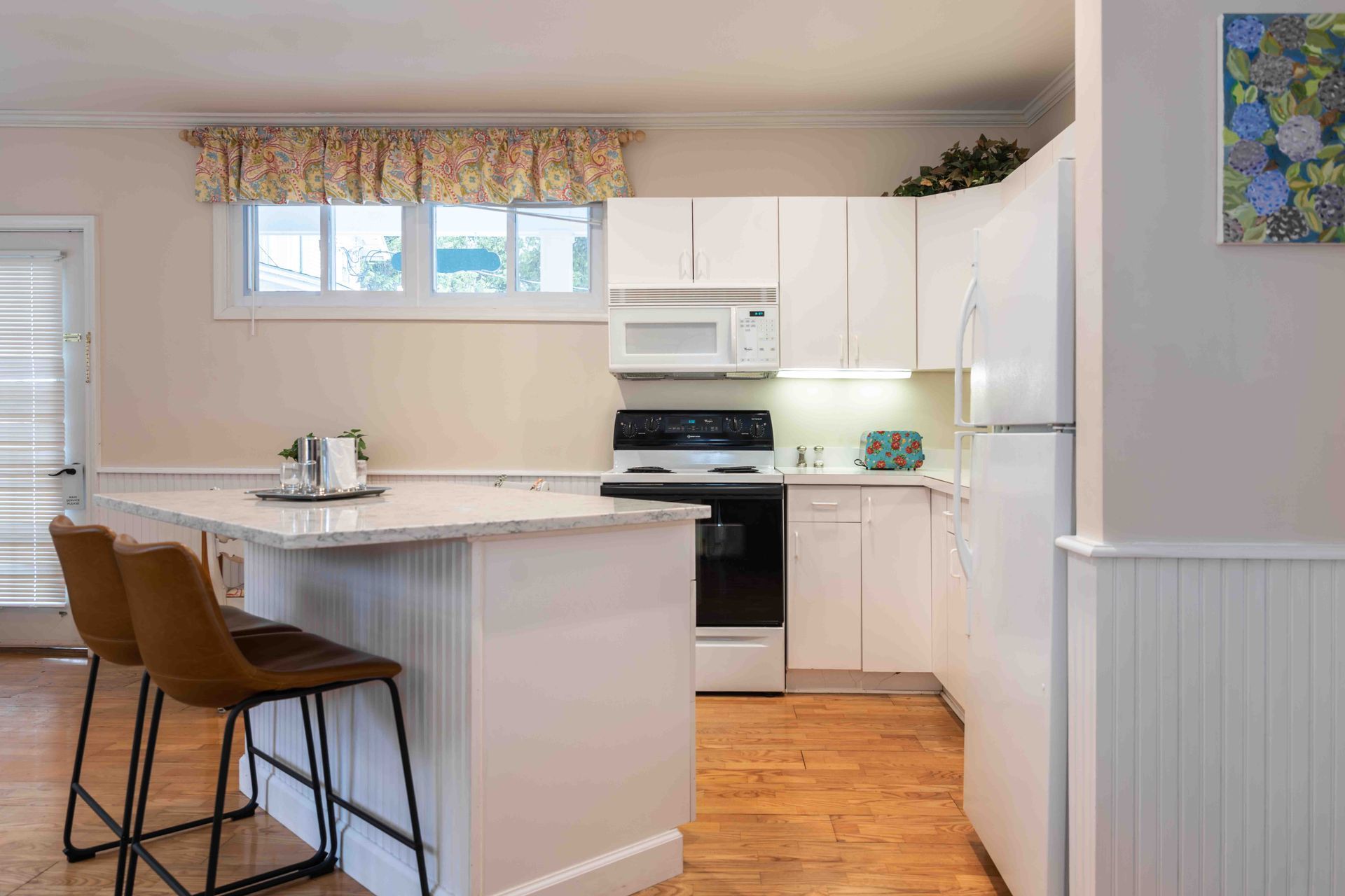 Bright kitchen with white cabinets, island seating, and stainless appliances in a cozy home interior