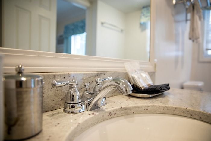 Bathroom sink with chrome faucet, soap dispenser, and a black comb on the countertop