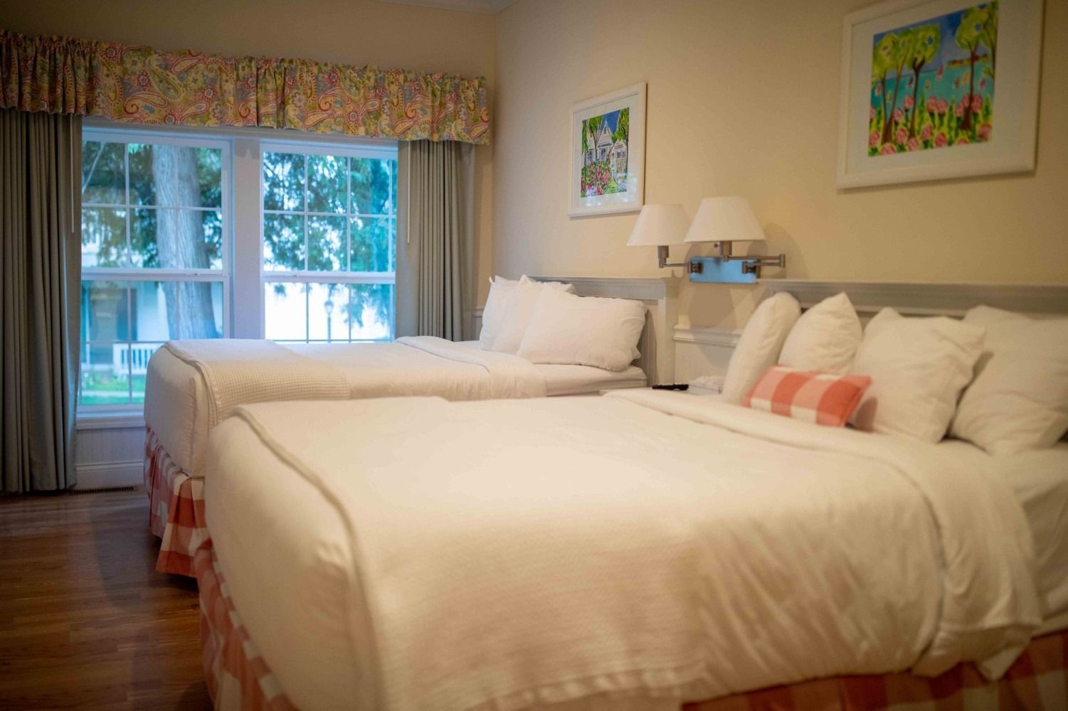 Hotel room with two white beds, large window, and colorful wall art