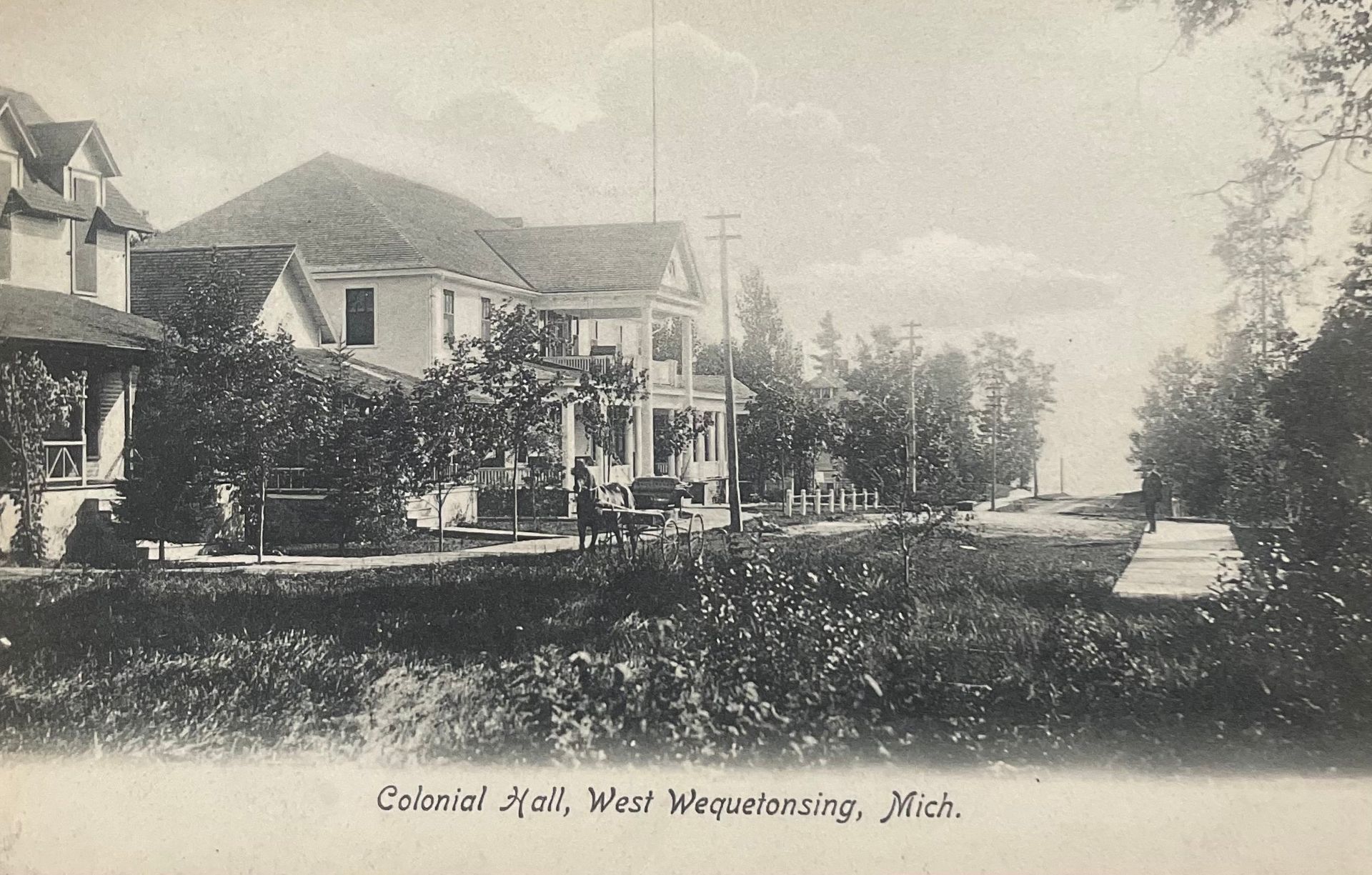 Historic lakeside hotel with houses, trees, and a dirt road along the waterfront