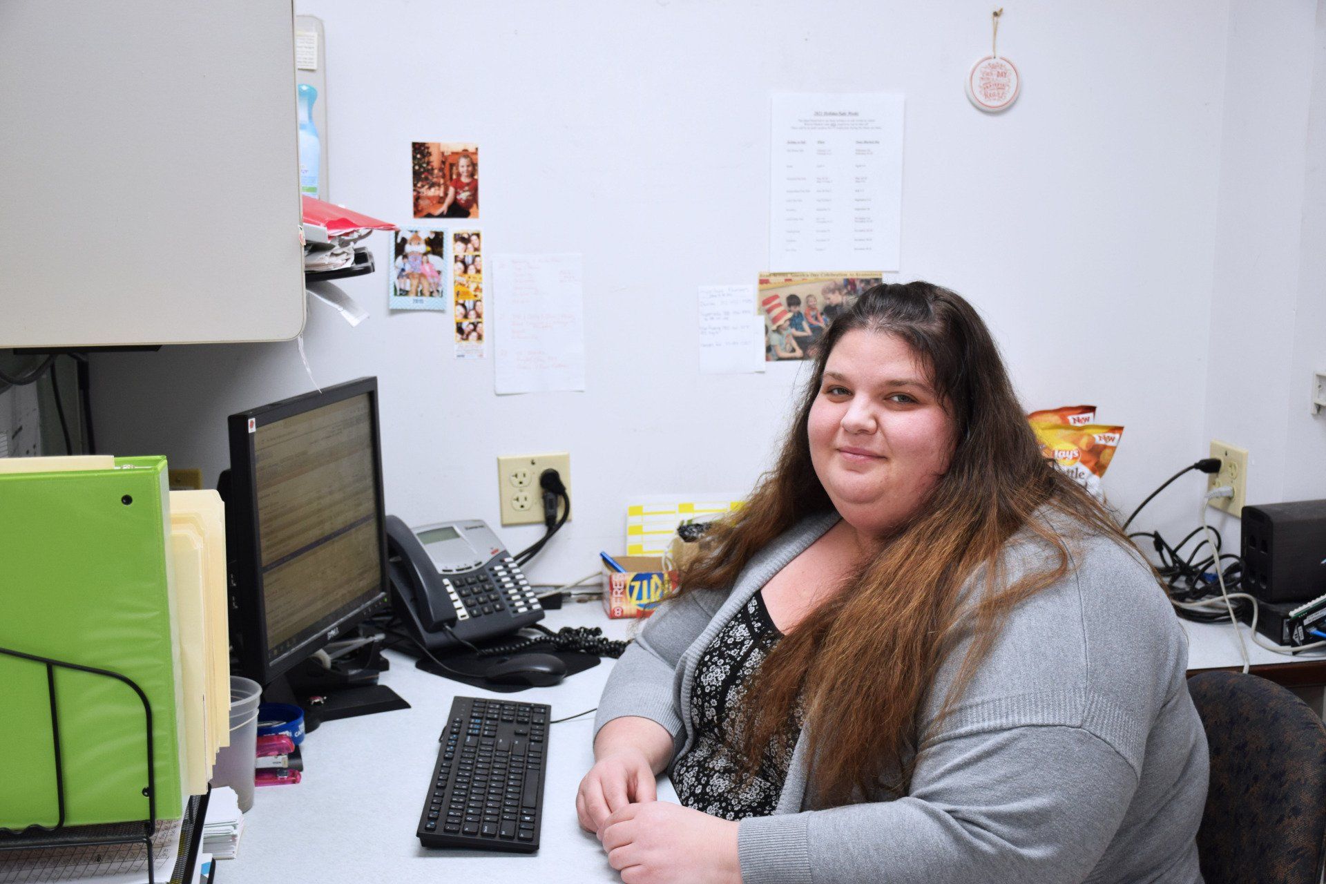 A woman is sitting at a desk in front of a computer.
