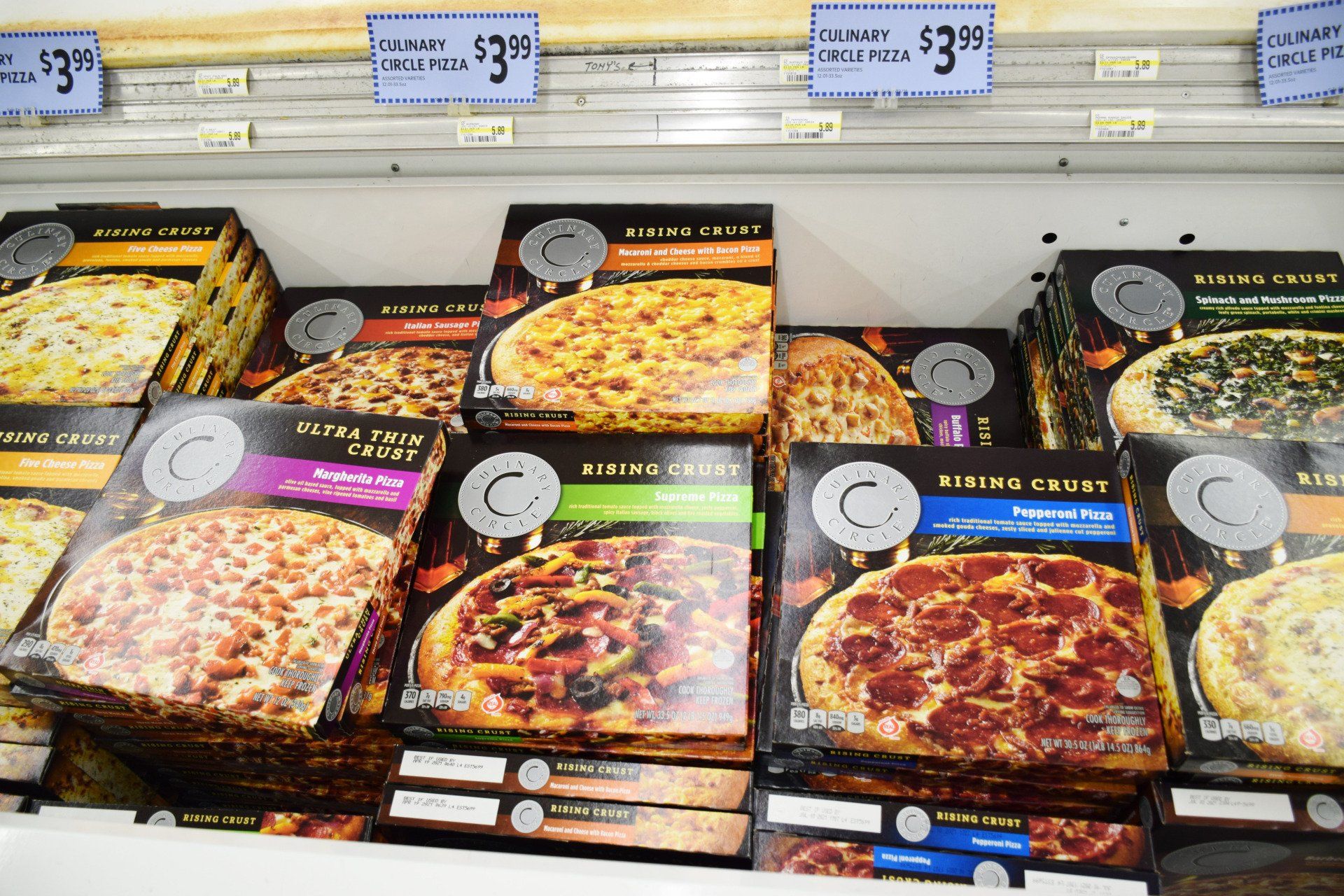 A variety of frozen pizzas are stacked on top of each other