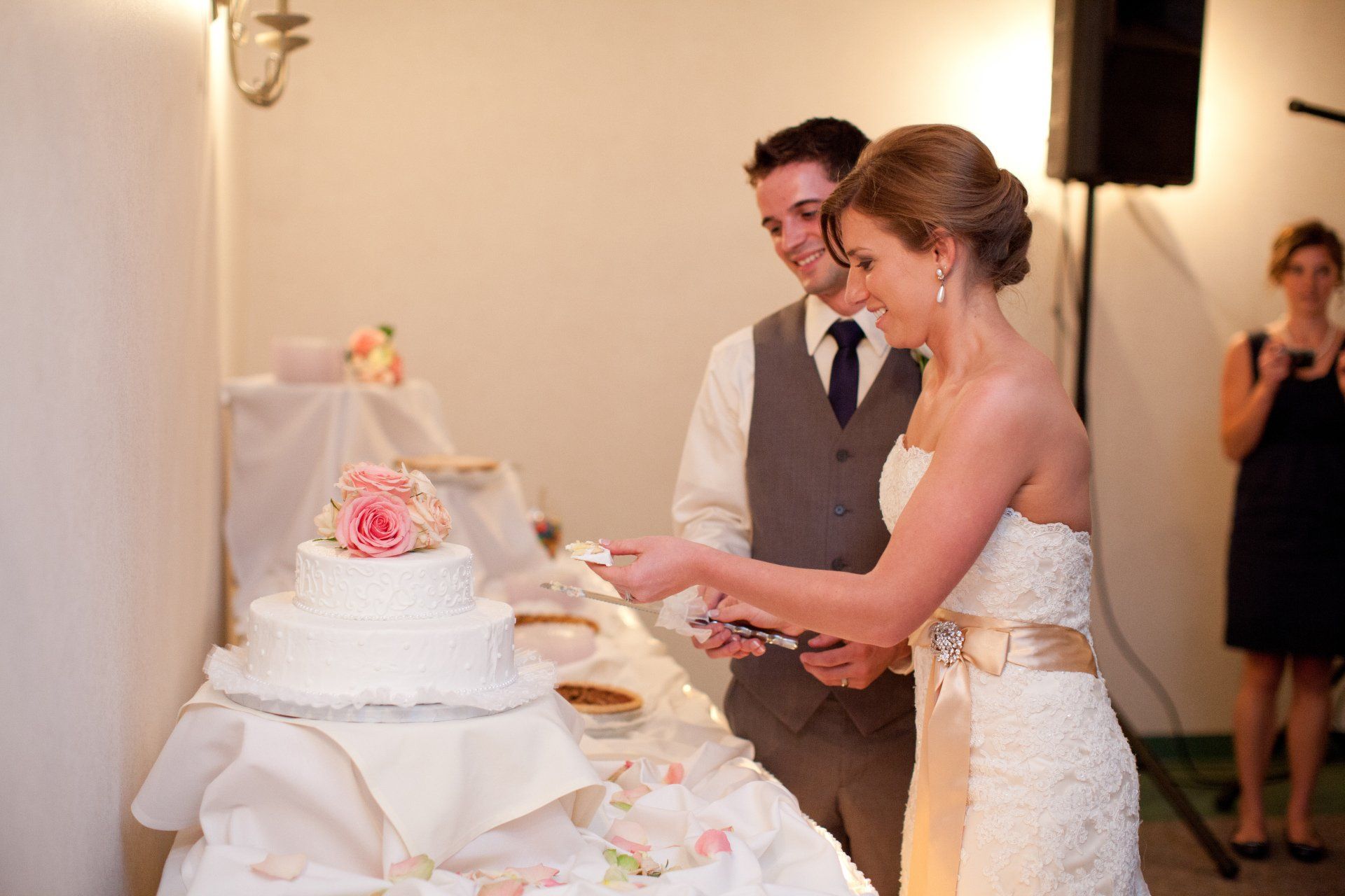 A bride and groom are cutting their wedding cake together