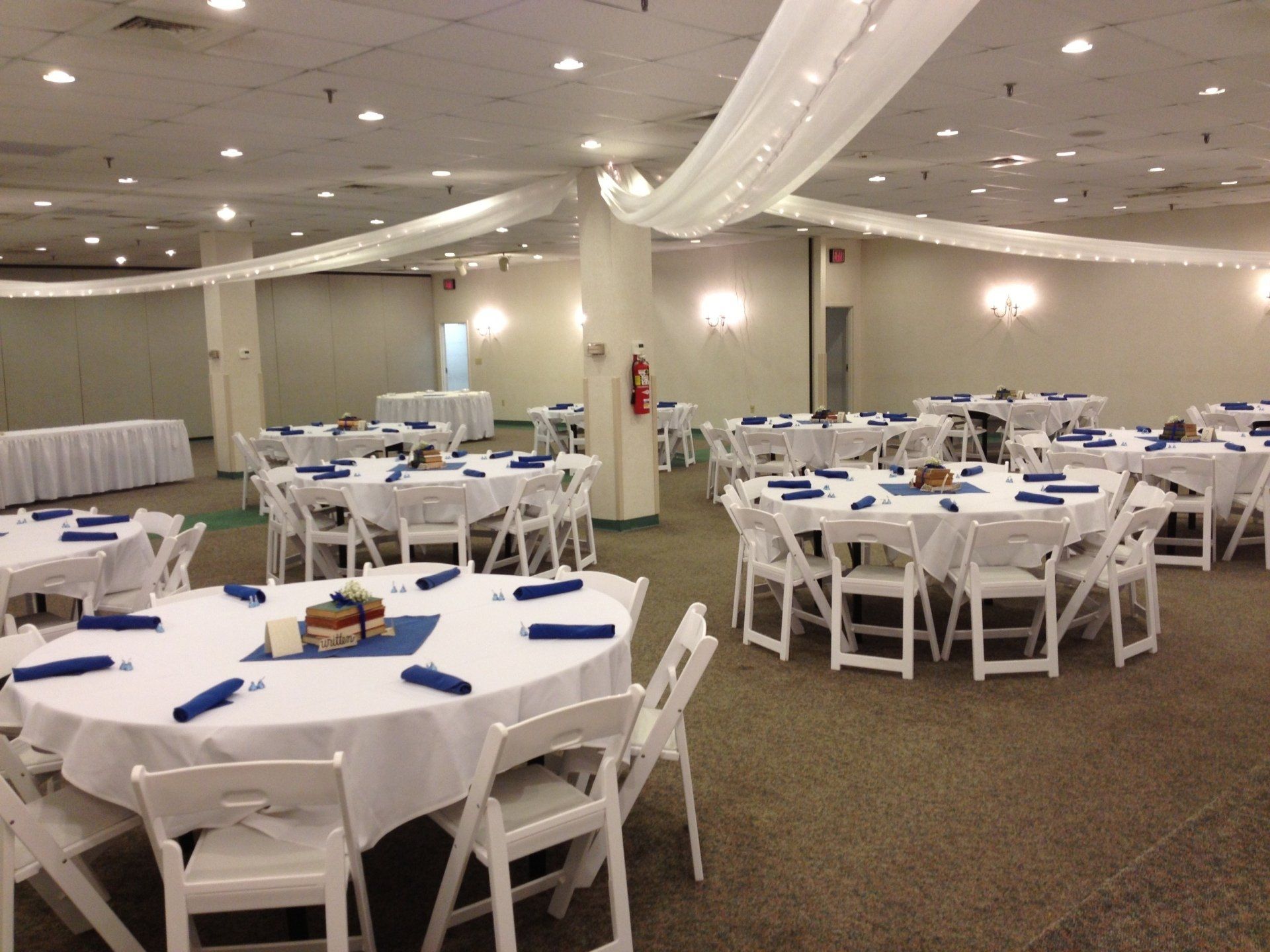 A large room with tables and chairs set up for a wedding reception