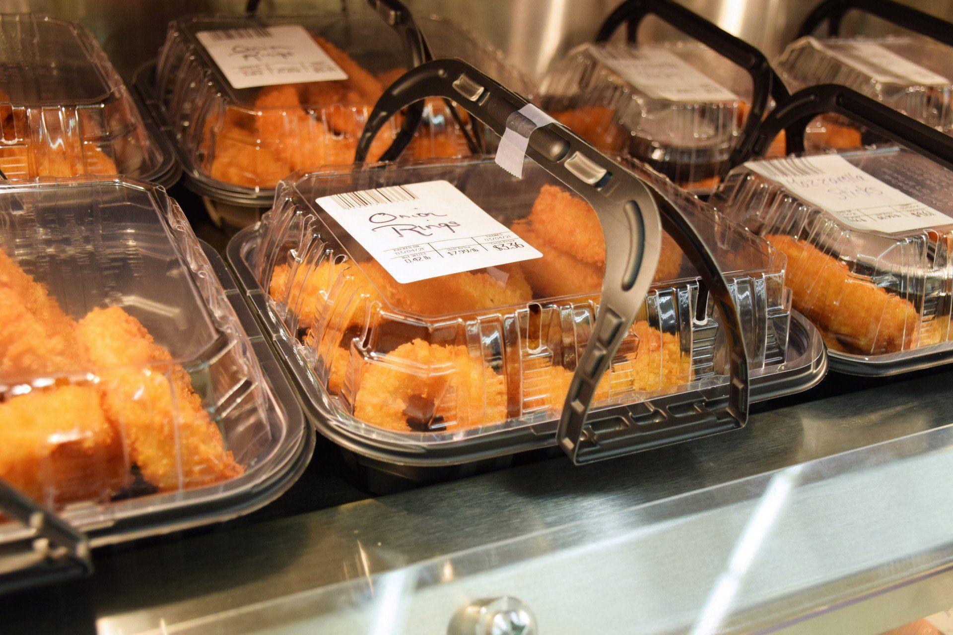 A display case filled with plastic containers of food including fried shrimp