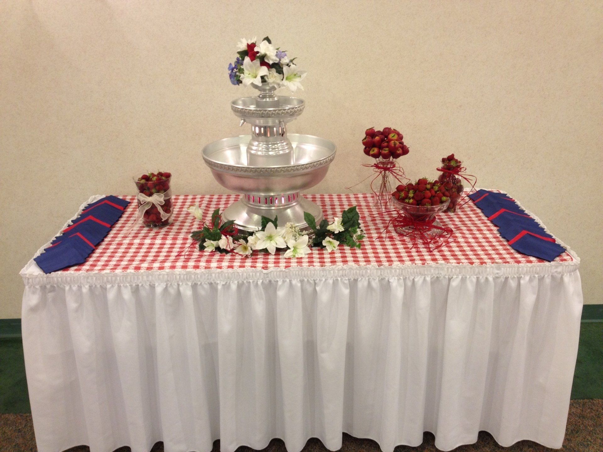 A table with a red and white checkered tablecloth and a fountain on top of it.