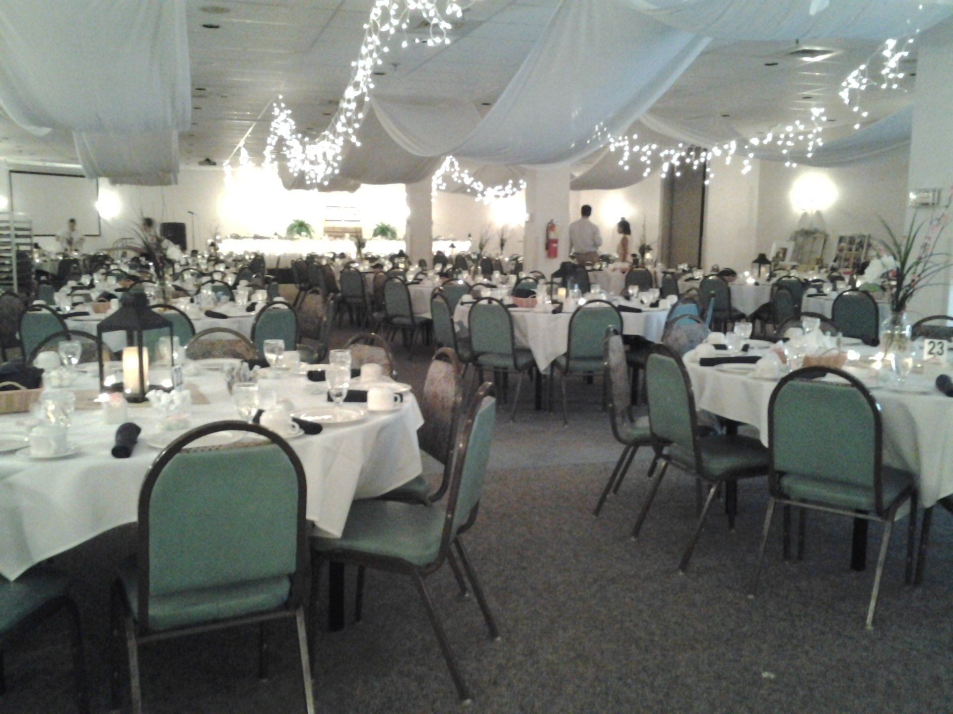A large room with tables and chairs set up for a wedding reception
