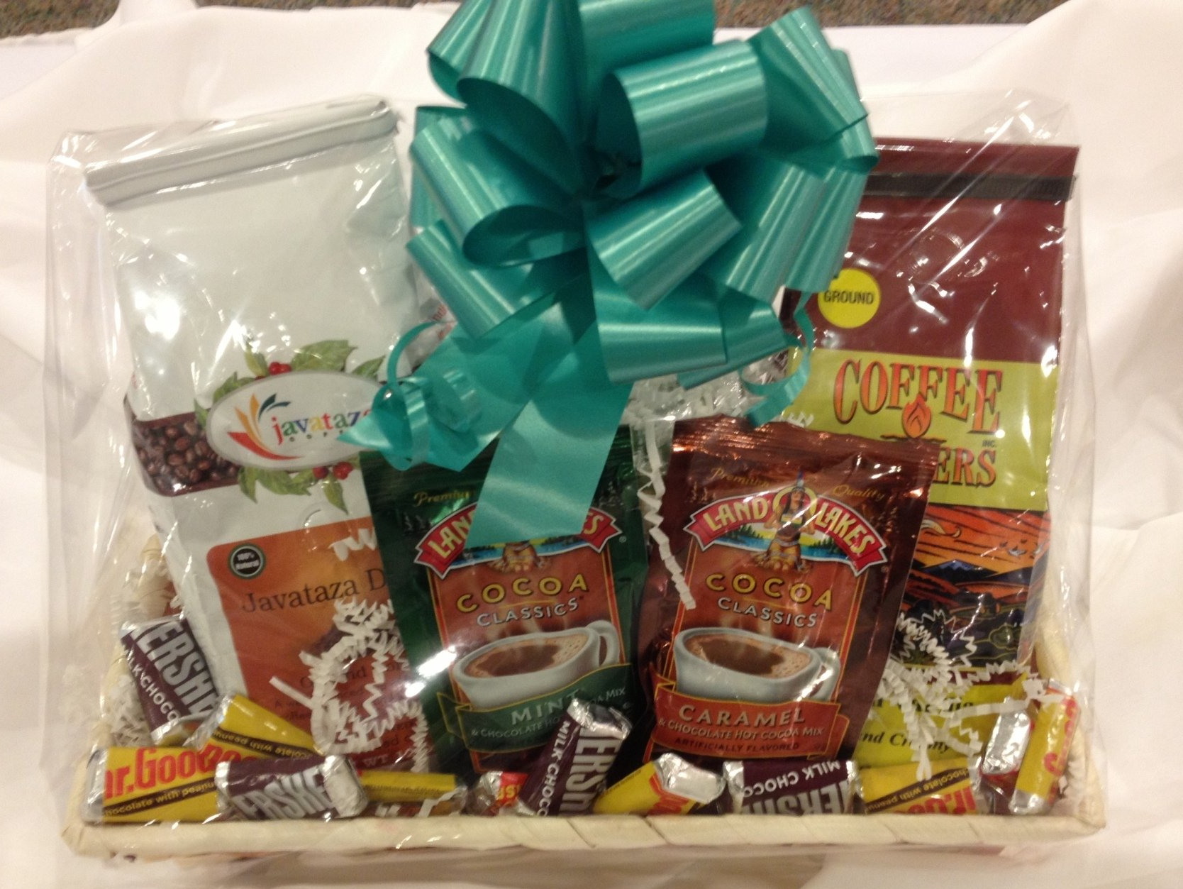 A basket filled with coffee and candy with a blue bow