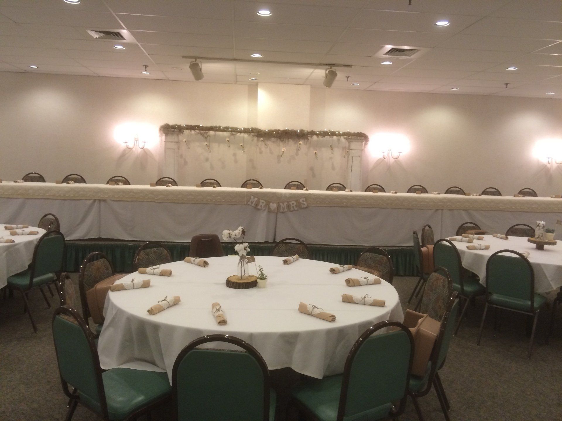 A large room with tables and chairs set up for a wedding reception