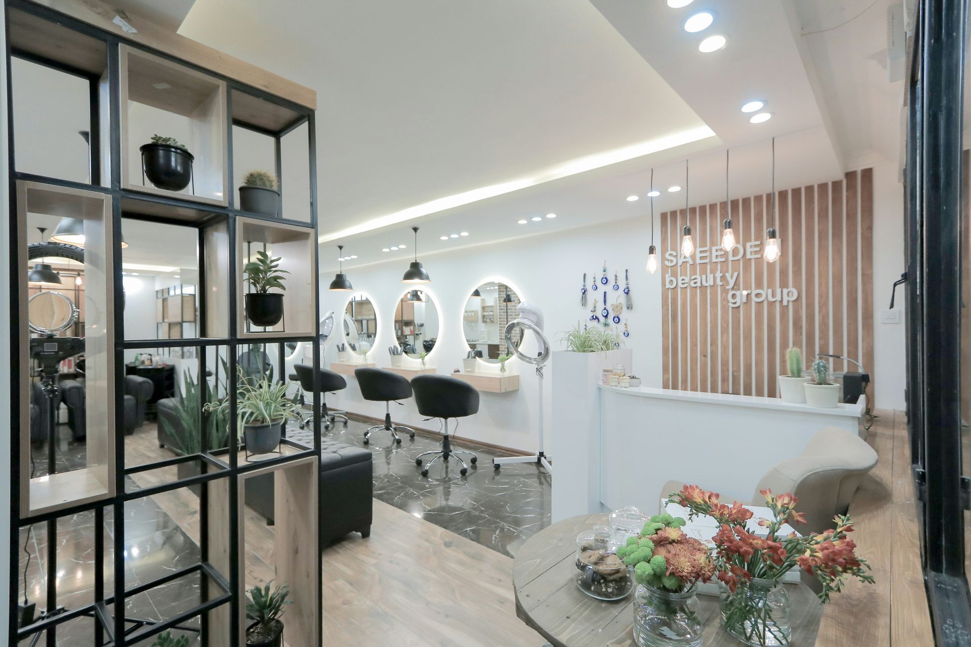 A bright, modern hair salon featuring wooden shelving, round mirrors, and a minimalist white reception area.