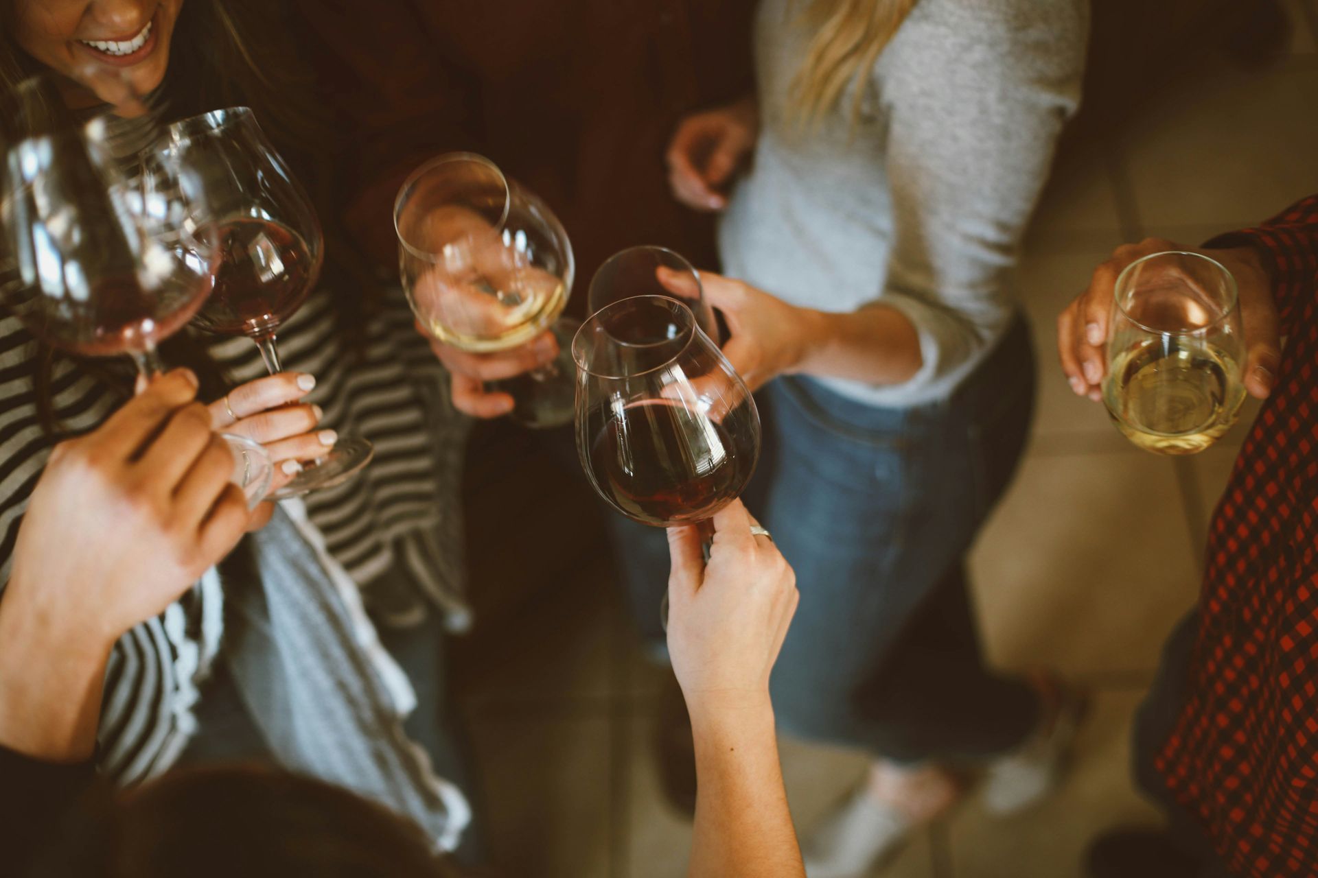 A group of people standing in a circle, clinking glasses filled with wine during a social gathering.