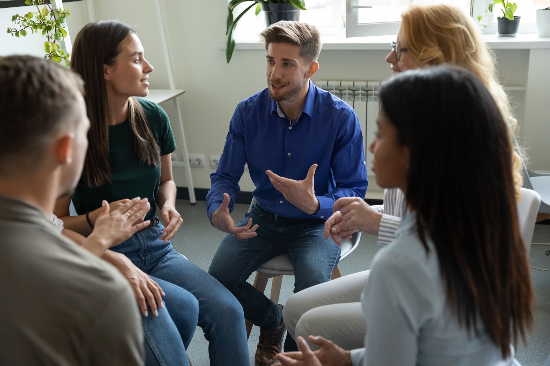 A Group of People Are Sitting in a Circle Talking to Each Other