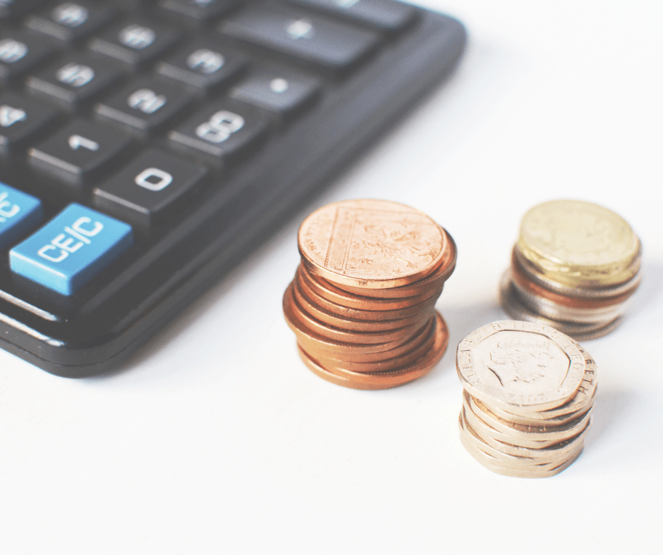 Calculator next to stacks of coins on a white surface. Calculator next to stacks of coins on a white surface.