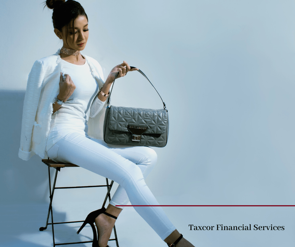 Woman in white suit holding grey purse, sitting on stool. Woman in white suit holding grey purse, sitting on stool.