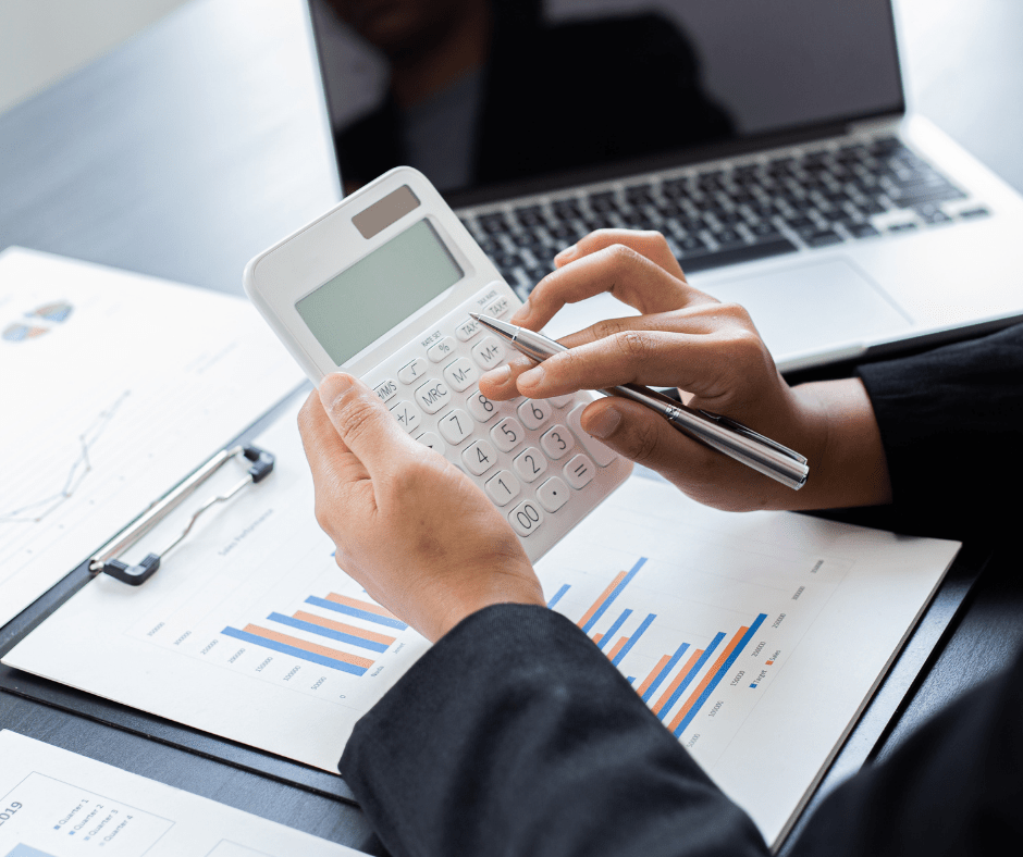 Hands using calculator, working on financial documents, laptop in background. Hands using calculator, working on financial documents, laptop in background.