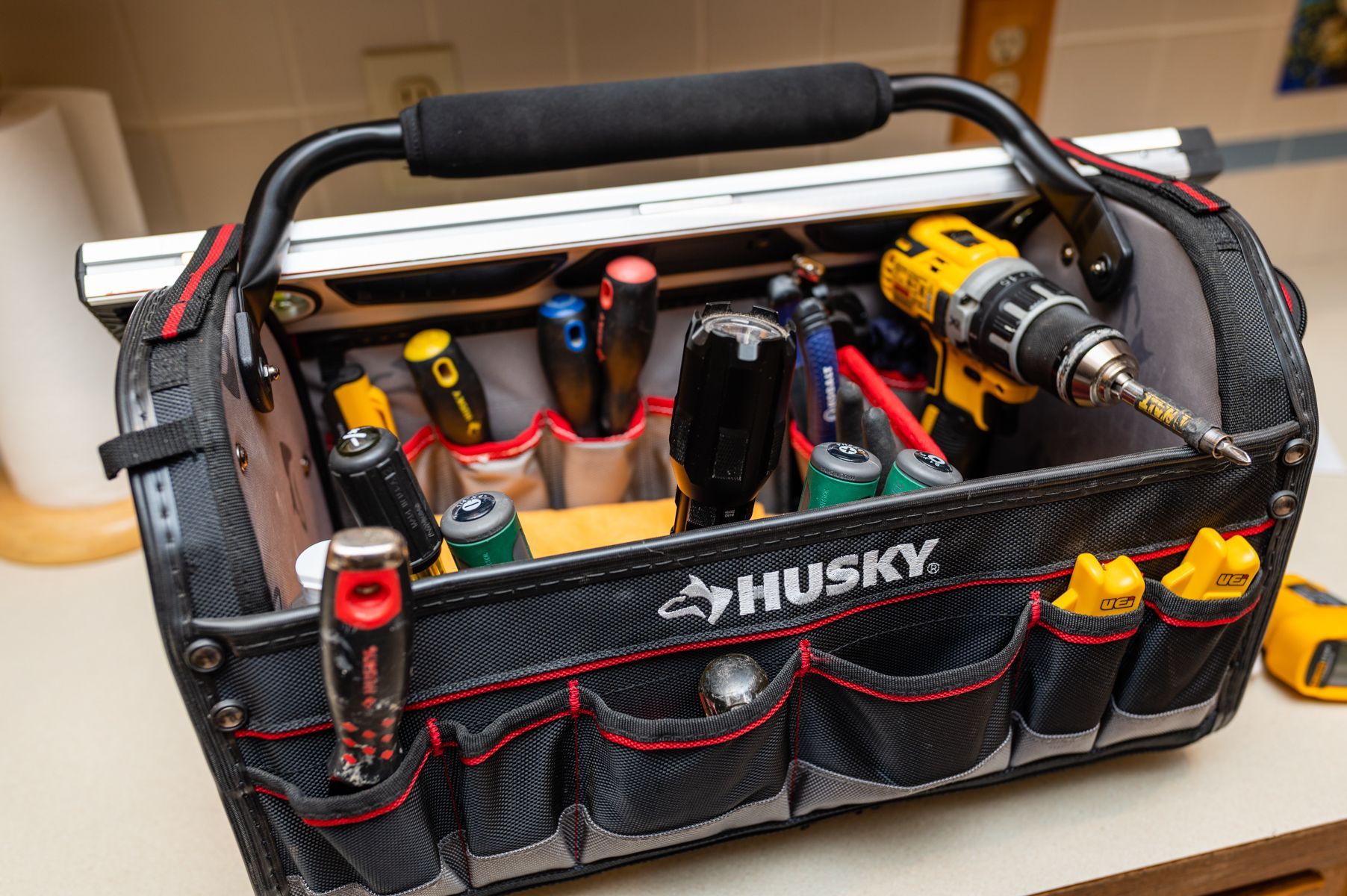 Husky tool bag filled with assorted hand tools and screwdrivers on a table