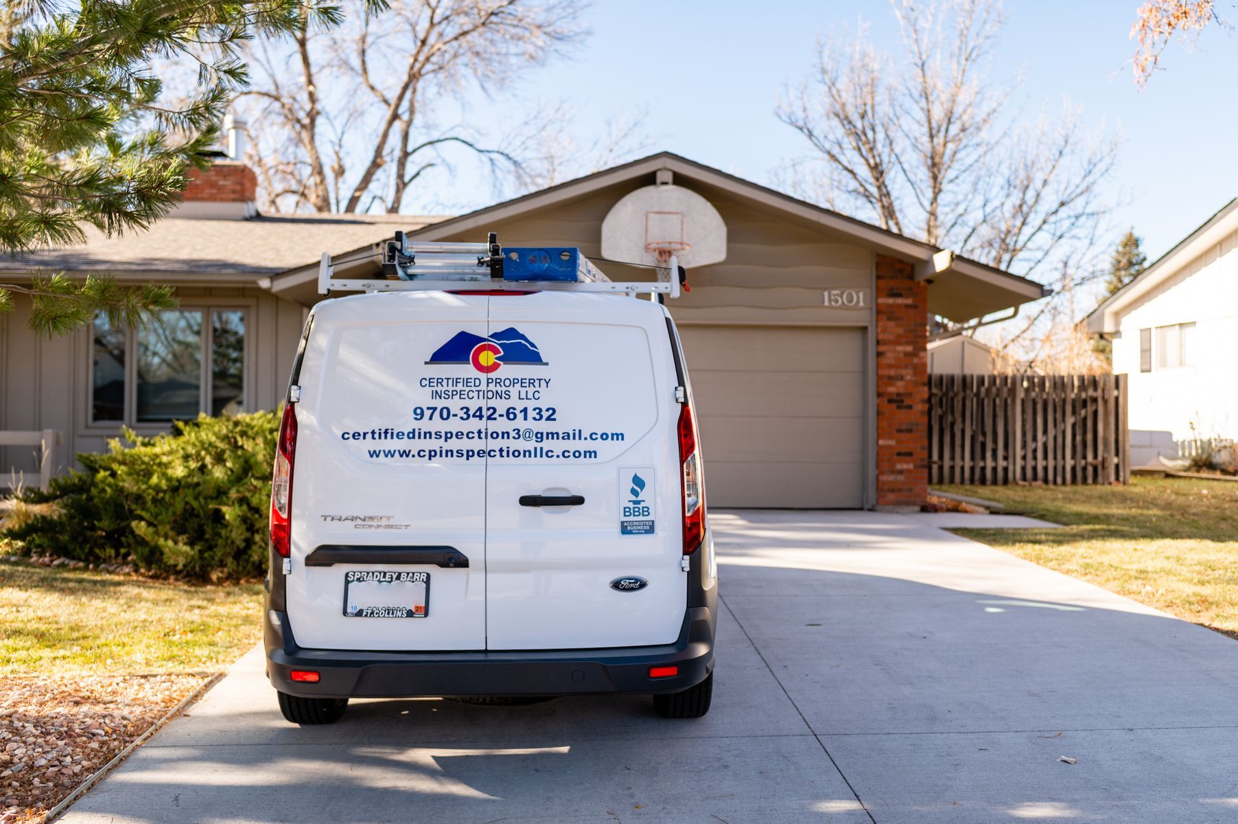 White service van parked in a suburban driveway in front of a brick house and garage.