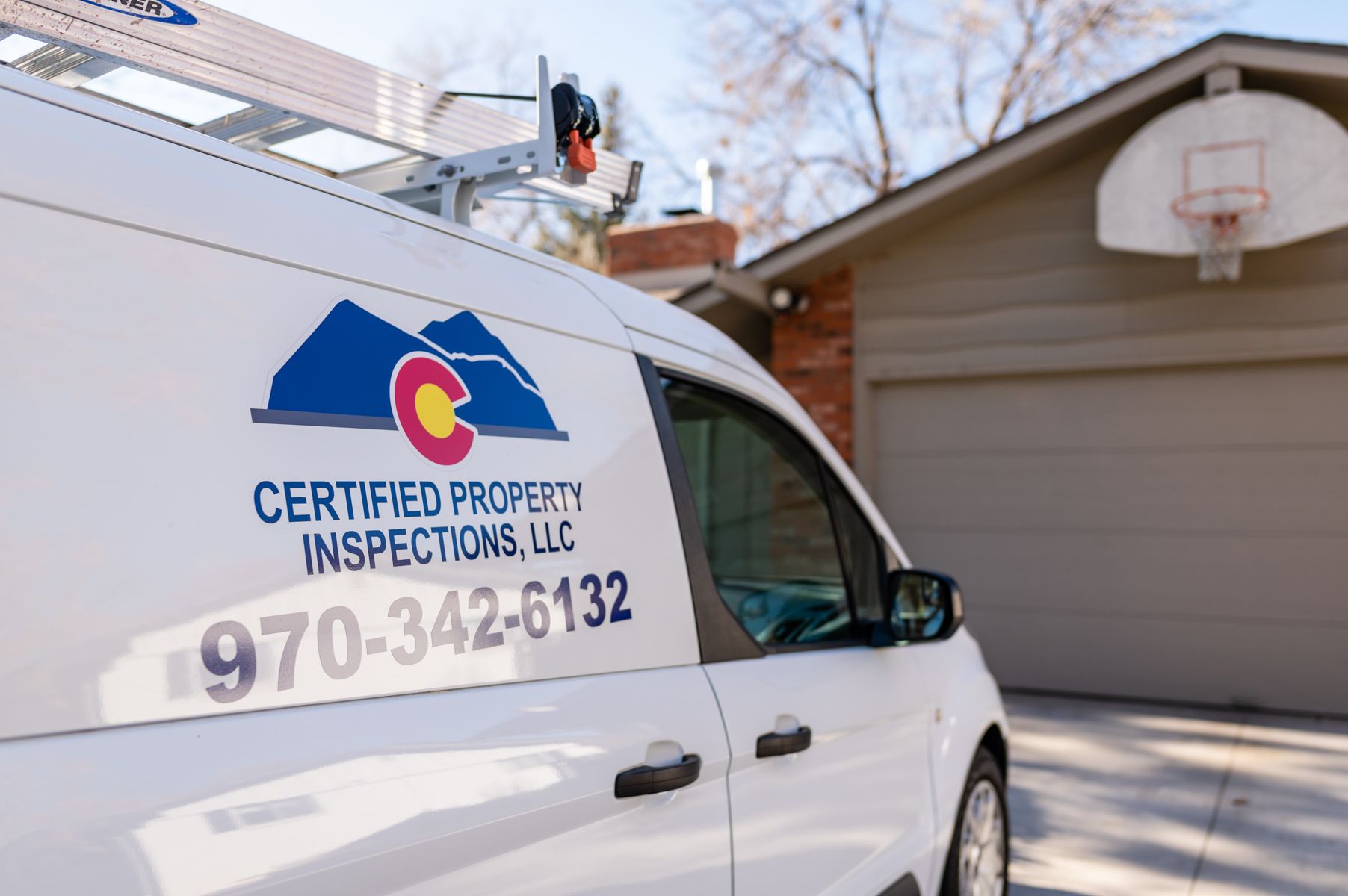 White inspection van with Certified Property Inspection LLC logo parked beside a house garage.