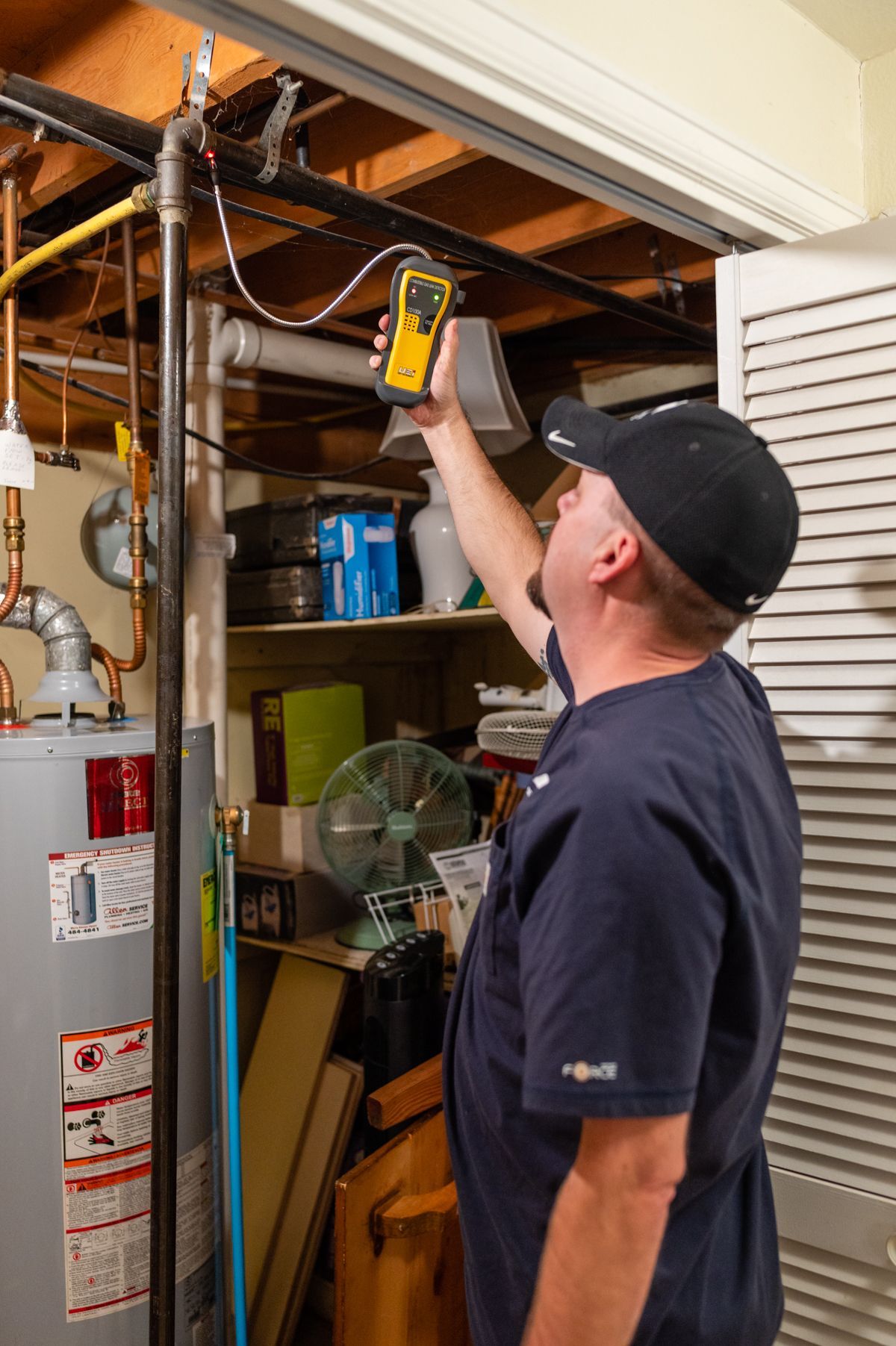 Technician using a handheld device to inspect wiring in an open garage ceiling