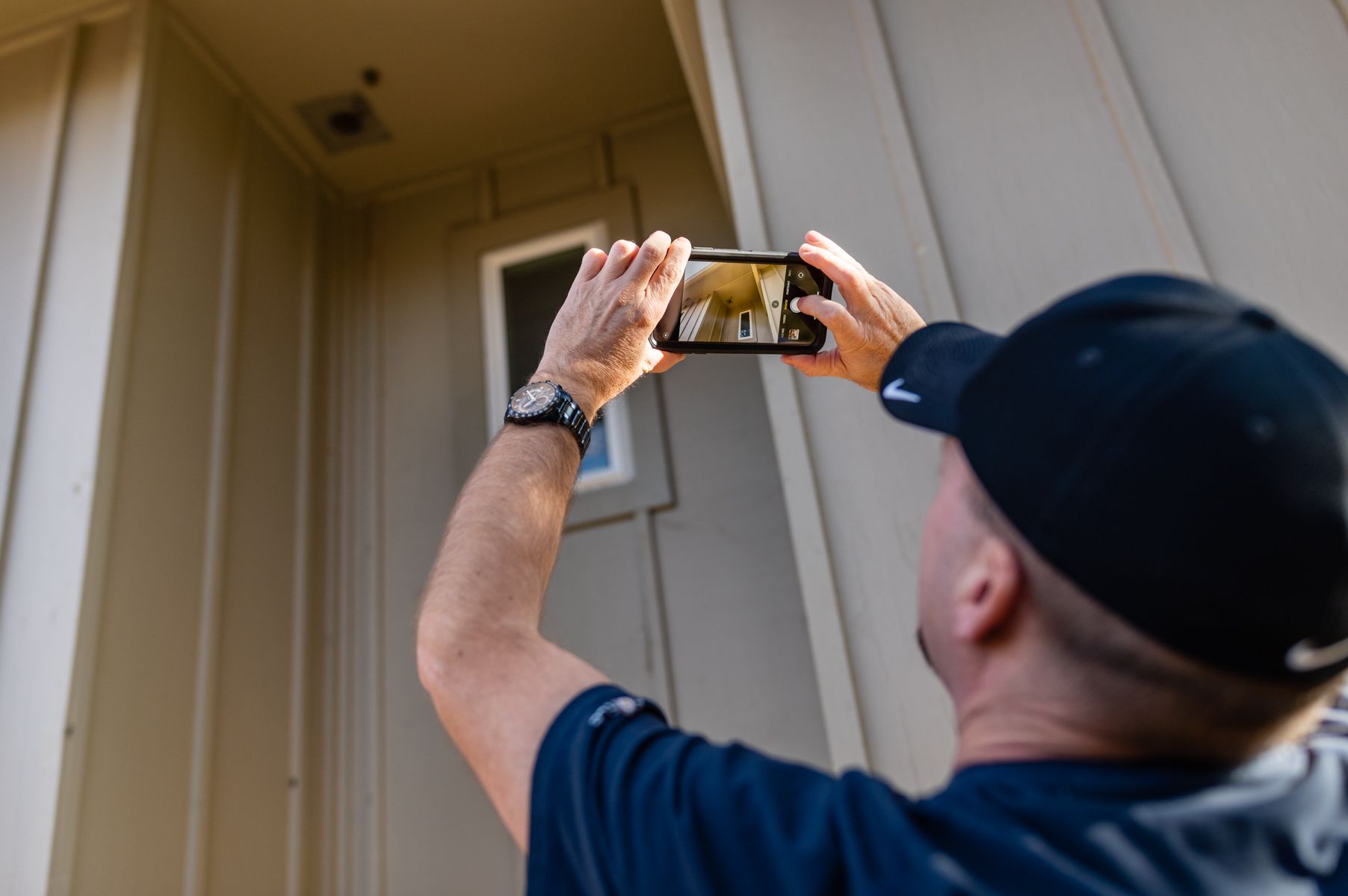 Person taking a photo of a house exterior with a smartphone.