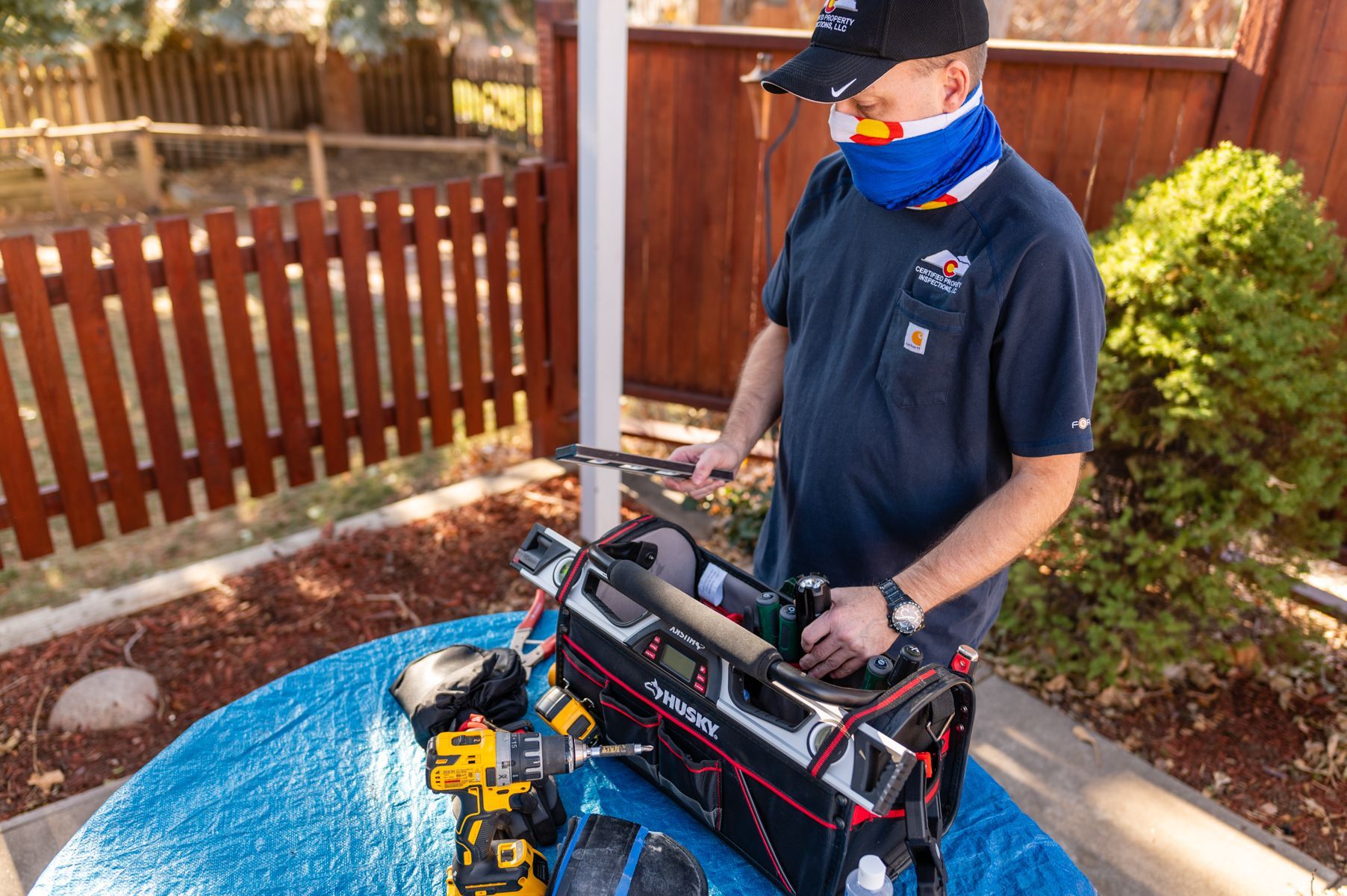 Person in a mask adjusting equipment beside a blue-topped table outdoors
