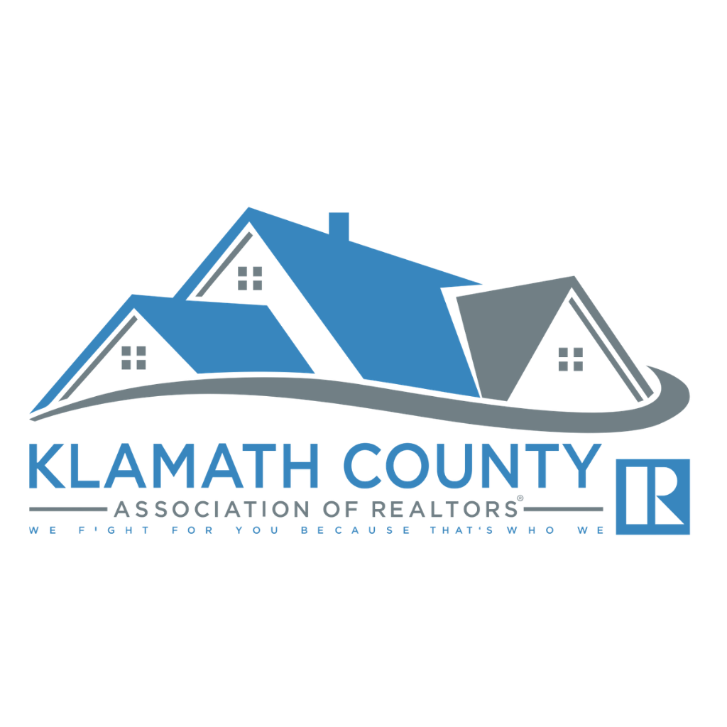 Logo for the Klamath County Association of Realtors, featuring a blue and gray house illustration over text and an R icon.