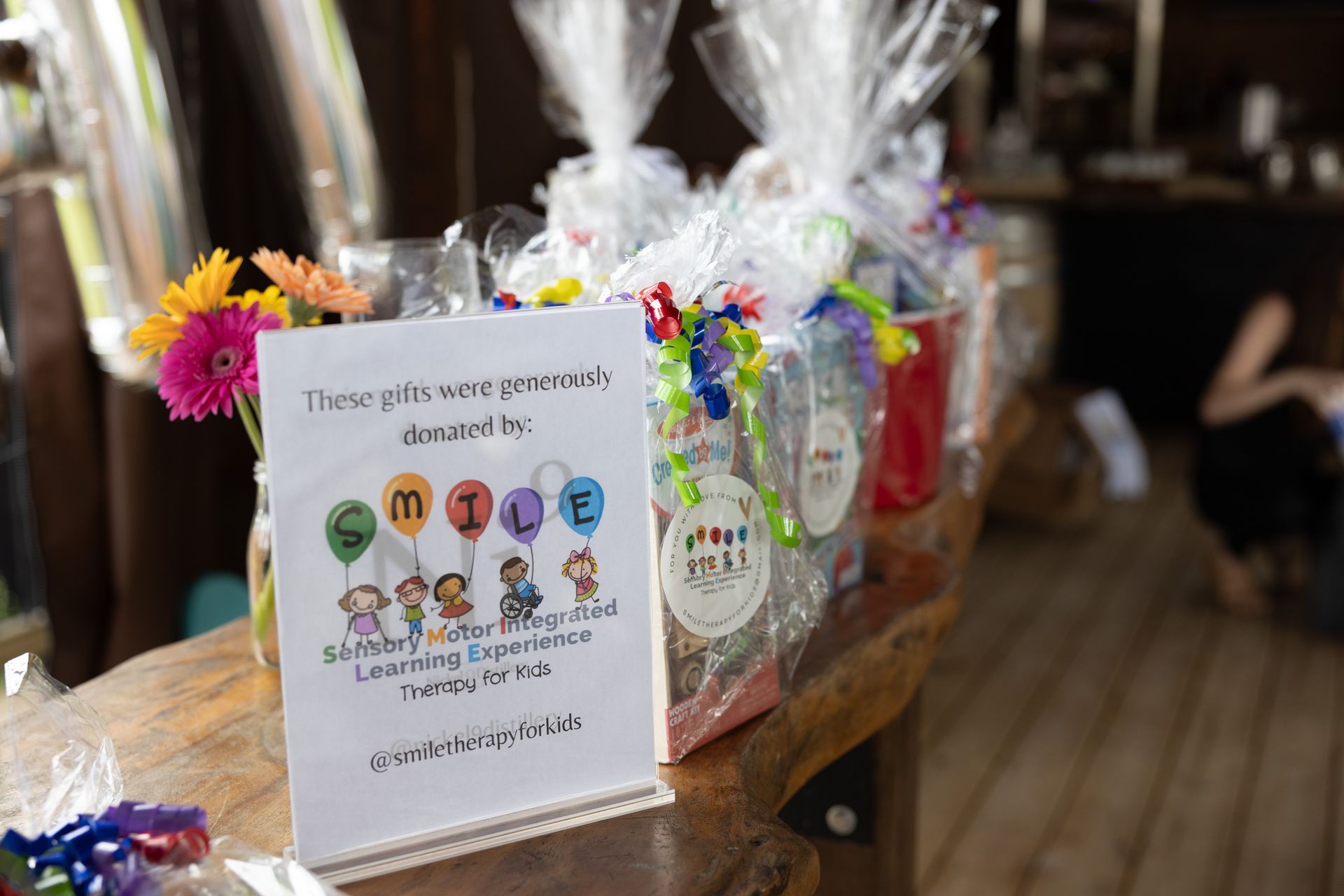 Gift baskets wrapped in cellophane on a wooden table, a sign that says
