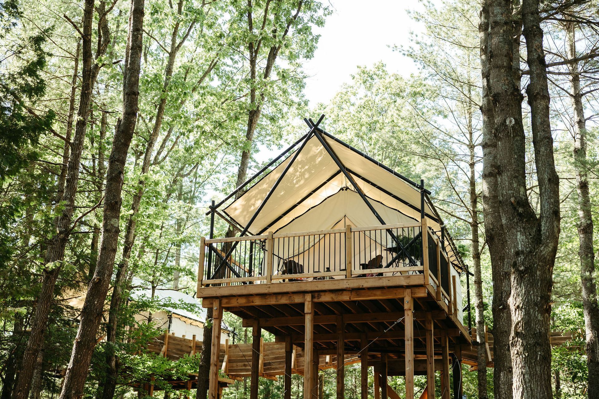 A raised wooden platform with a tent structure in a forest setting.