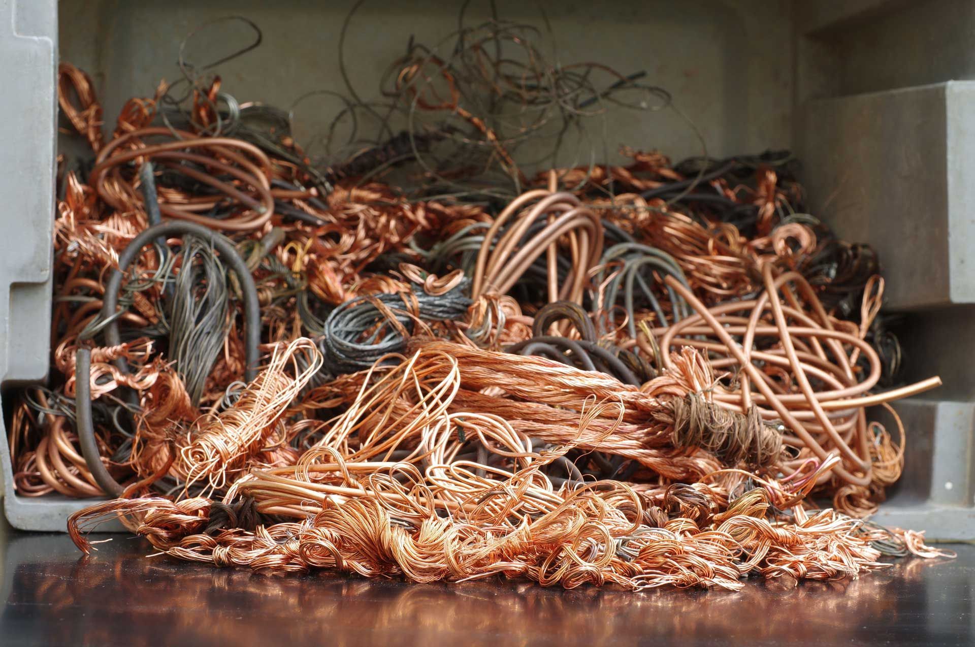 Pile of copper wire scrap in a gray container, ready for recycling.
