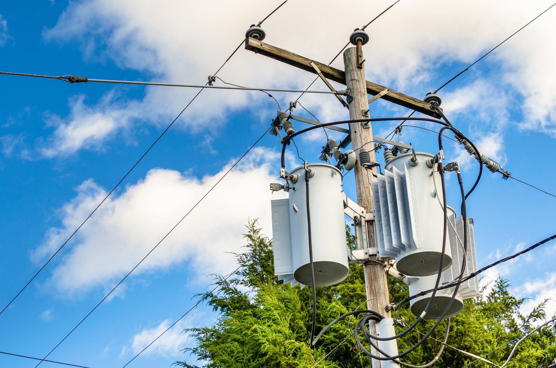 Transformers — Lewisville, TX — AAA Recycling, Inc. Power pole with transformers against a blue sky with clouds.