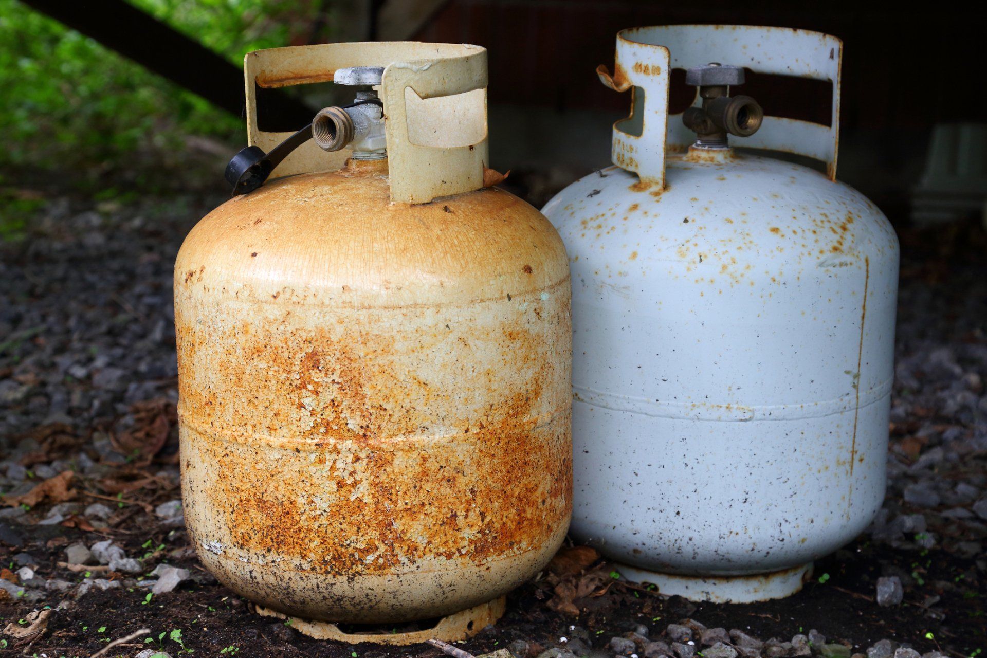 Pressurized Containers — Lewisville, TX — AAA Recycling, Inc. Two weathered propane tanks, one rusty orange, the other white, sit outdoors.