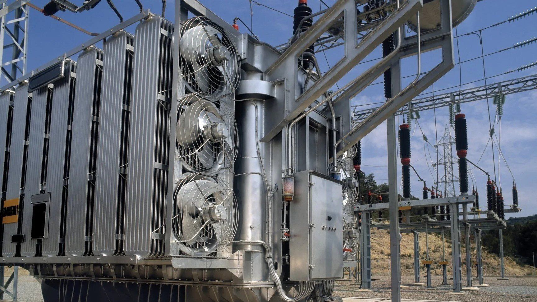 Transformer — Lewisville, TX — AAA Recycling, Inc. Large electrical transformer at a power station, cooling fans visible, blue sky in the background.