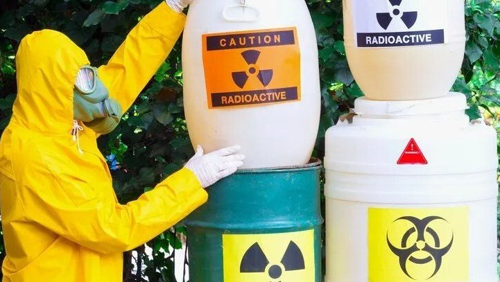 Radioactive Materials — Lewisville, TX — AAA Recycling, Inc. Person in yellow hazmat suit near barrels labeled