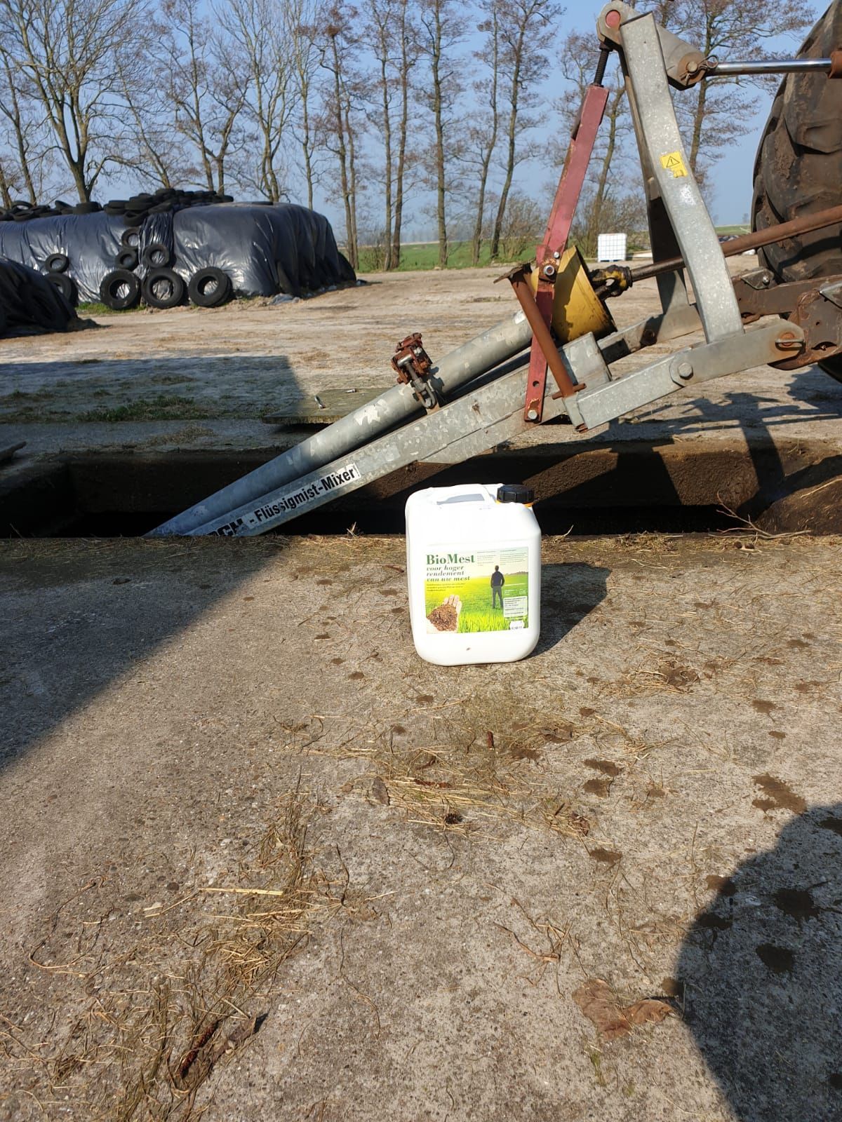 boerenbedrijf open afwateringssloot, bouwmachines en een witte waterkan op grind. met een can BioMest