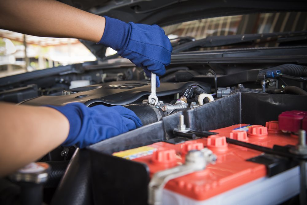A Person Is Working On A Car Battery With A Wrench — Marshall Batteries & Cairns Mobile Batteries In Manunda, QLD
