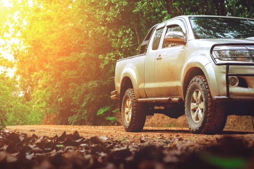 A Pickup Truck Is Parked On A Dirt Road In The Woods — Marshall Batteries & Cairns Mobile Batteries In Manunda, QLD
