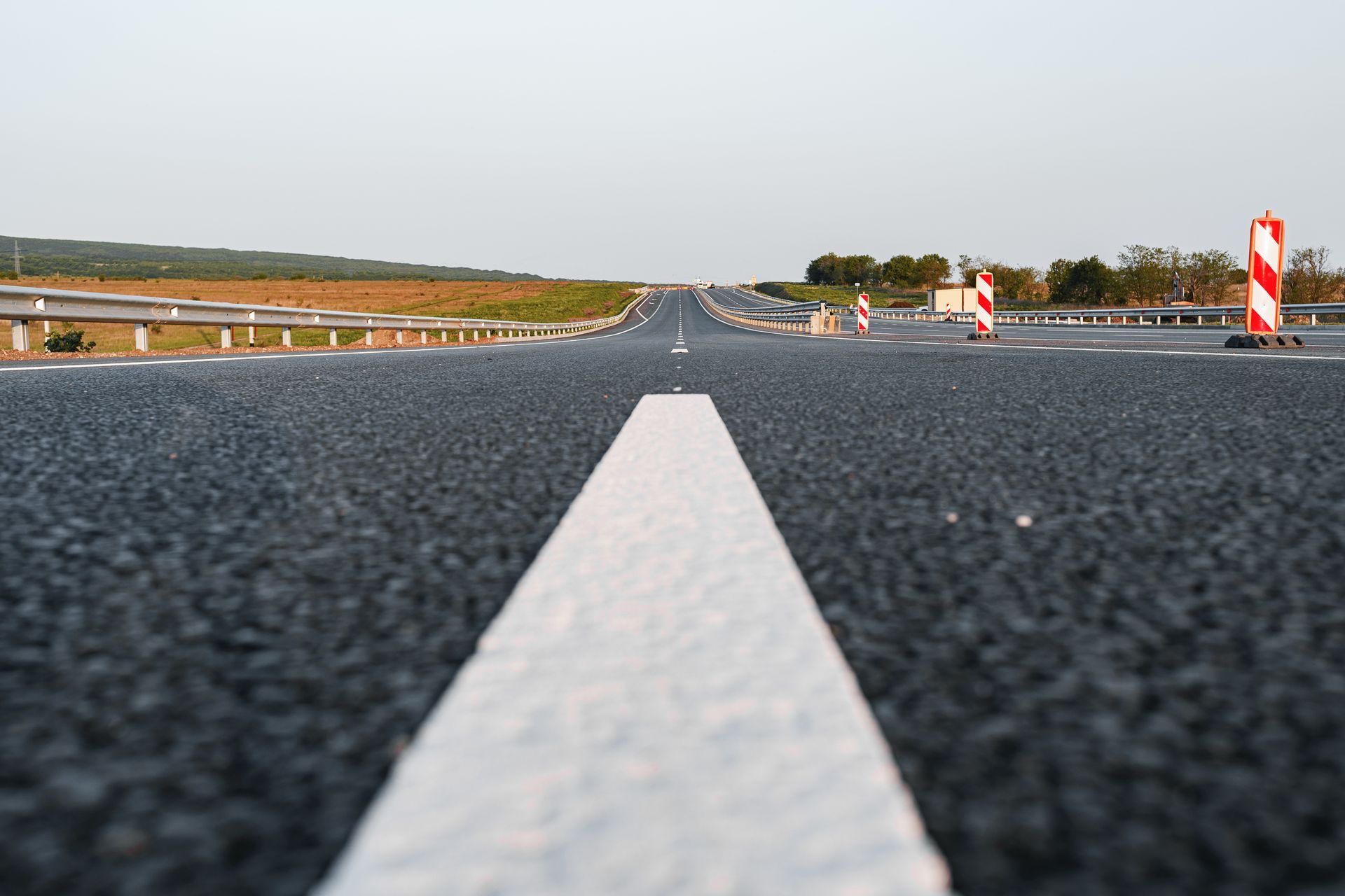 Low-angle view of a paved road with a white center line stretching into the distance under a clear sky